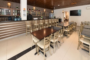 Un restaurante con barra, varias mesas y sillas.