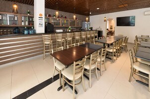 Un restaurante con barra, varias mesas y sillas.