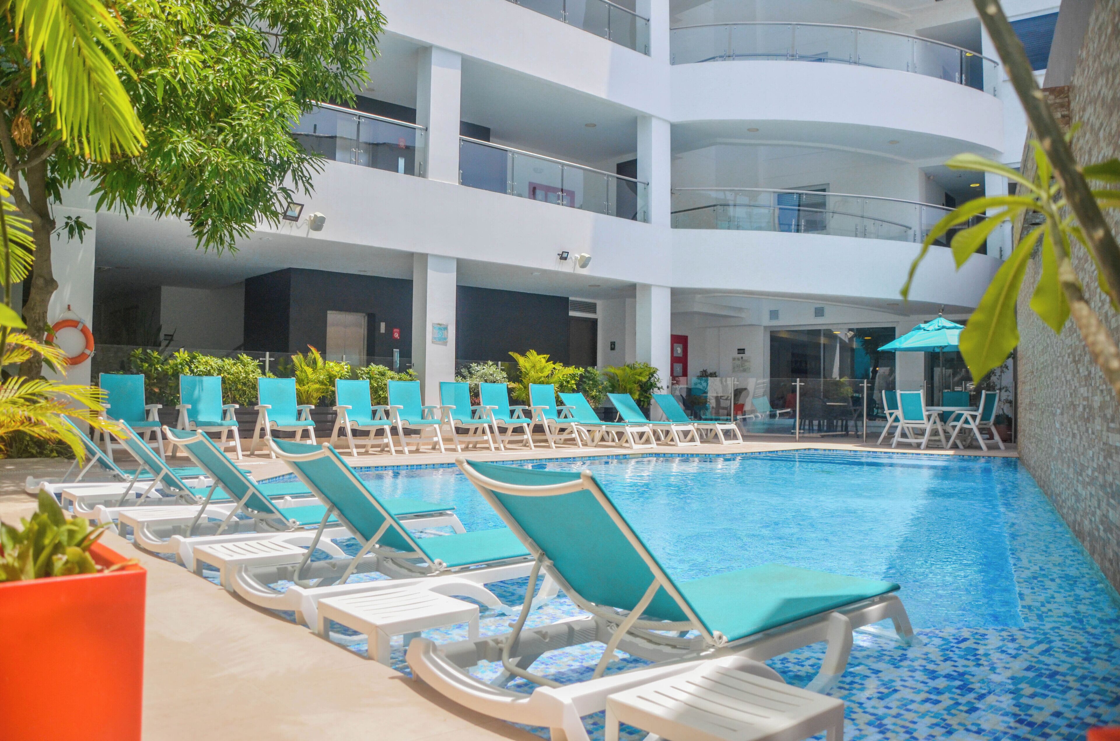 Una piscina al aire libre, sombrillas, sillones reclinables de piscina