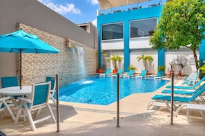Una piscina con sillas de descanso y una cascada.
