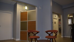 A hallway with wooden flooring, a sliding door, and two orange chairs. - The Urban San Francisco (San Francisco)