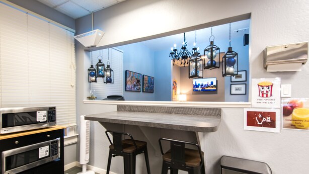 A kitchen with a bar area, two stools, a microwave, an oven, and a trash bin. - The Urban San Francisco (San Francisco)