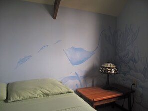 A room with a bed, a nightstand, a lamp, and a wall mural.