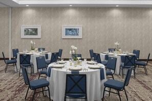 A conference room with round tables, blue chairs, and framed pictures on the walls. - Hilton Garden Inn San Marcos (San Marcos)