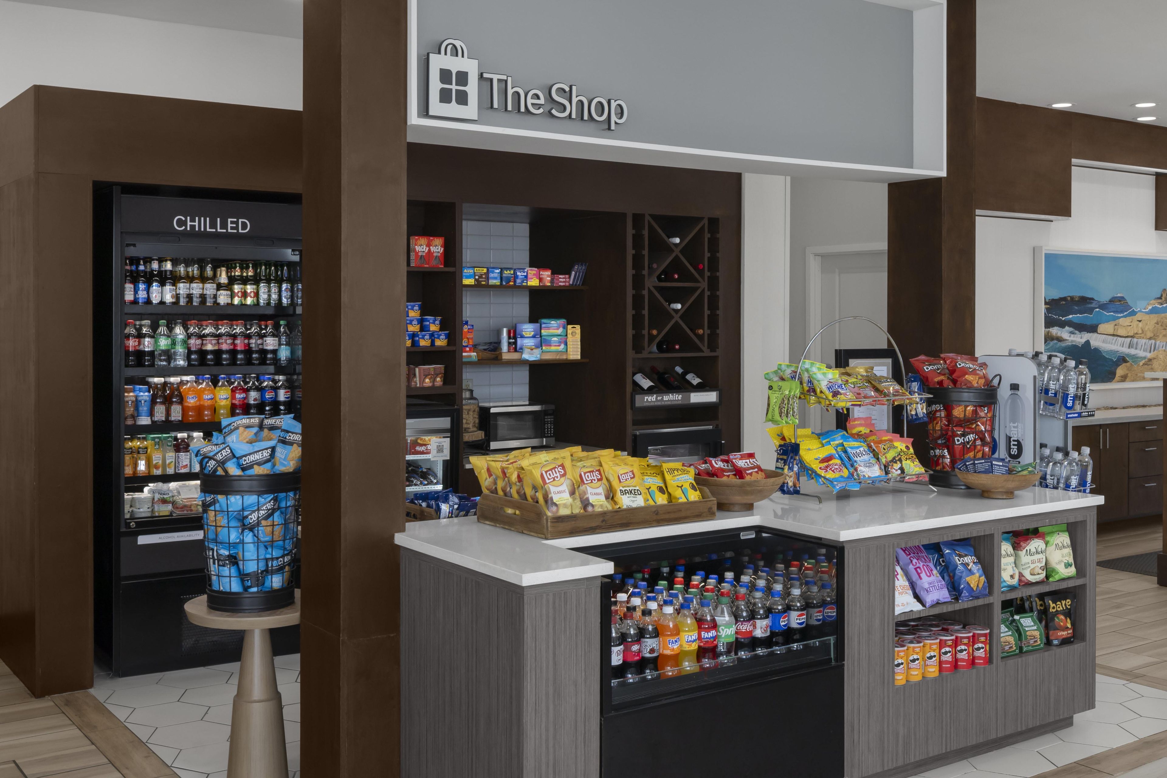 Una tienda con una sección de bebidas frías, exhibiciones de aperitivos y una variedad de productos envasados.