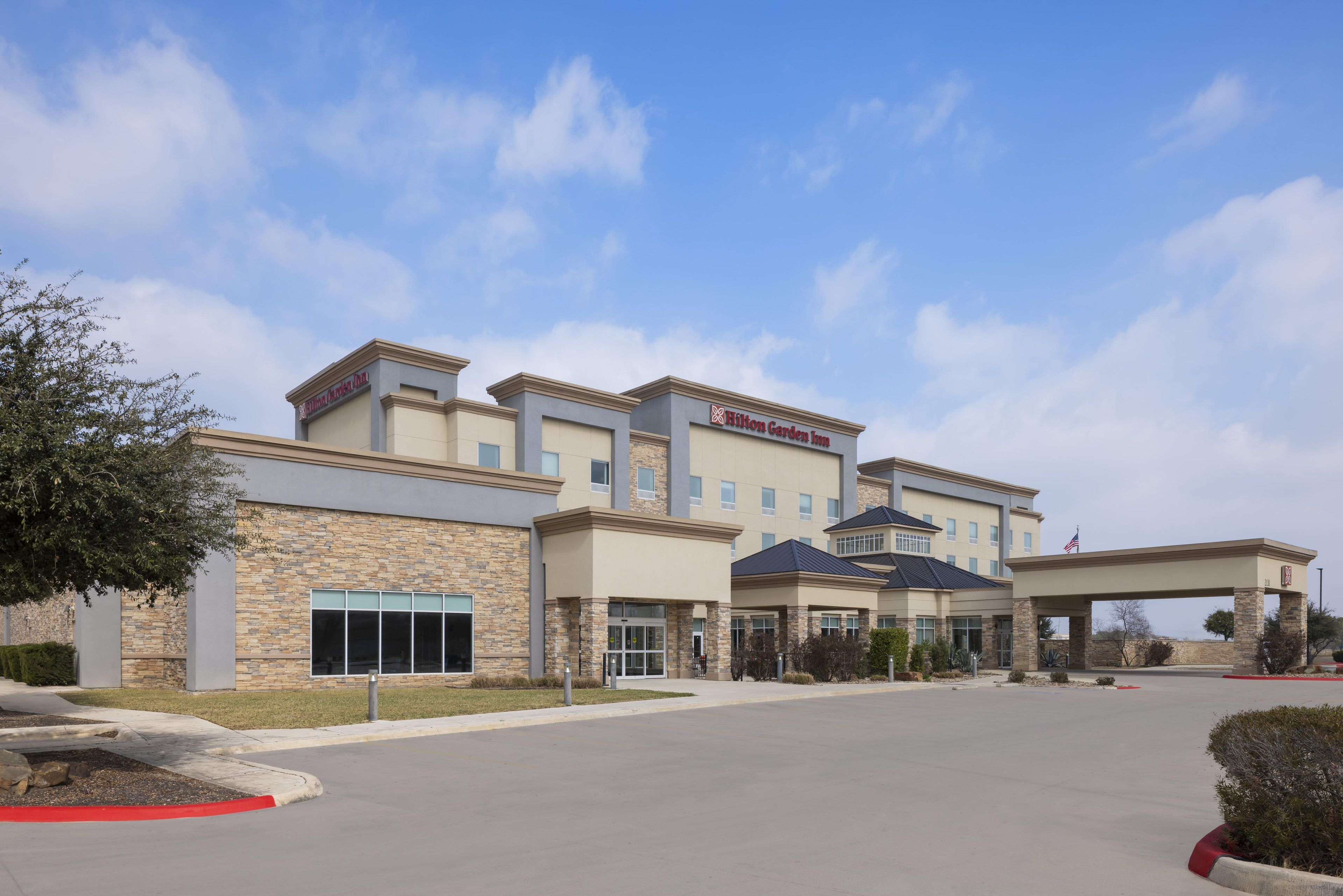 A hotel with a stone facade, a covered entrance, and a clear sky.