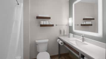 A modern bathroom with a toilet, sink, and shower. There are wooden shelves with towels and toiletries.