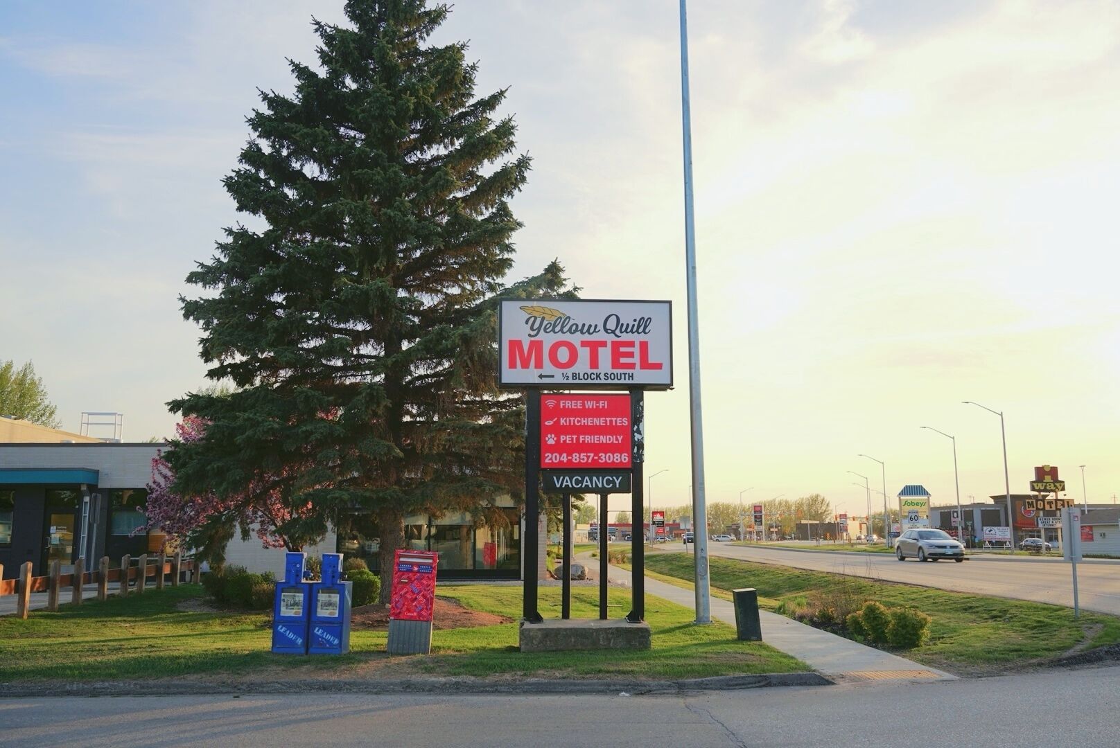 A motel sign with a vacancy notice, a phone number, and amenities like free Wi-Fi and kitchenettes.