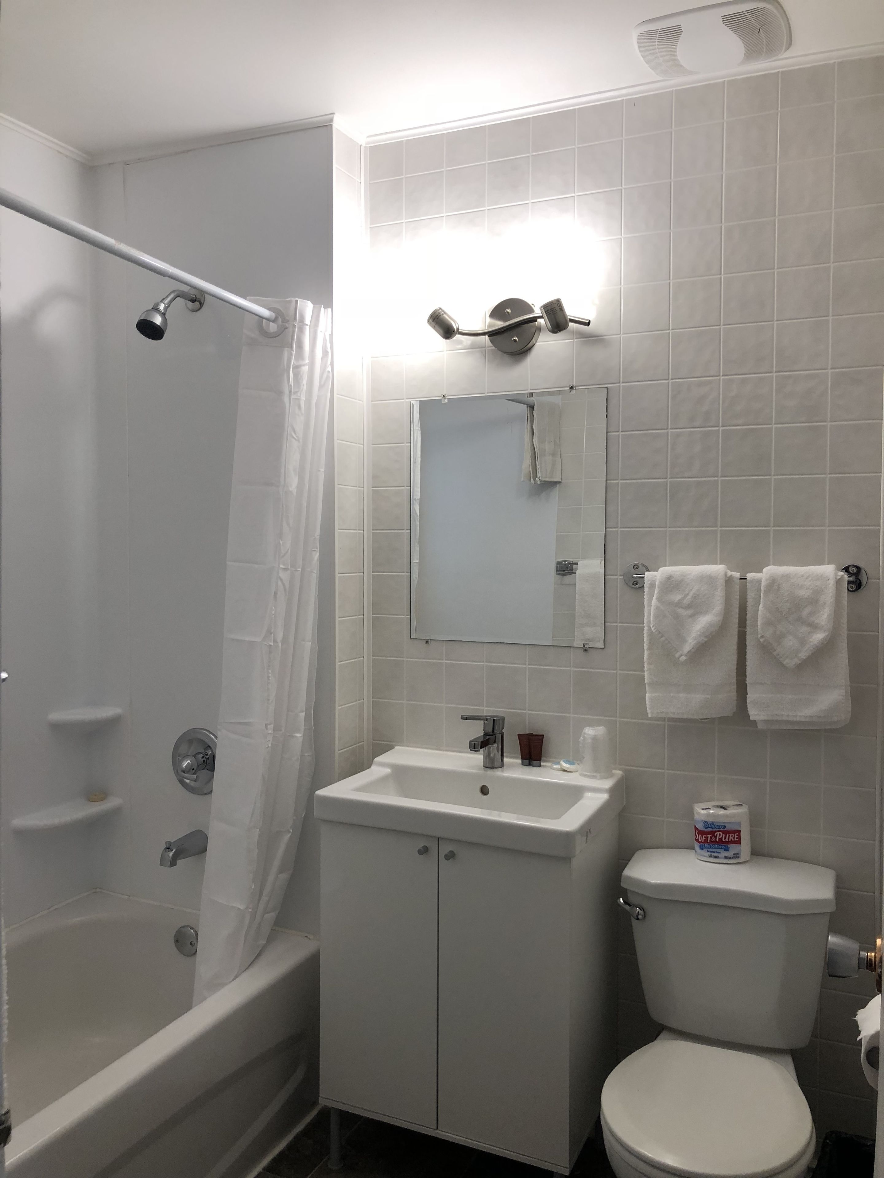 Un baño con bañera, lavamanos, inodoro y cortina de ducha.