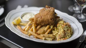 Un plato de pescado con patatas fritas y ensalada de col.
