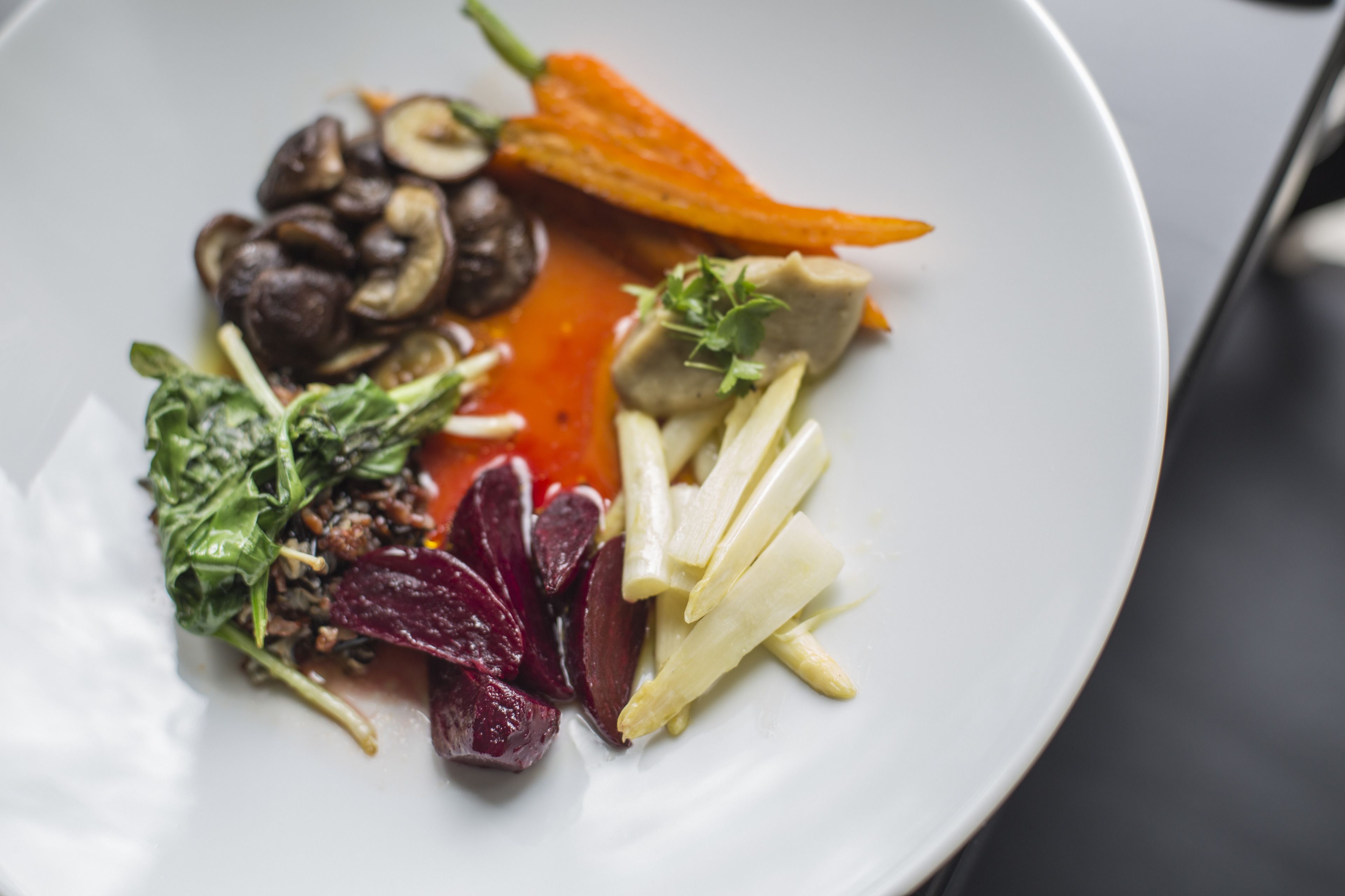 A plate with various food items including mushrooms, carrots, and leafy greens.