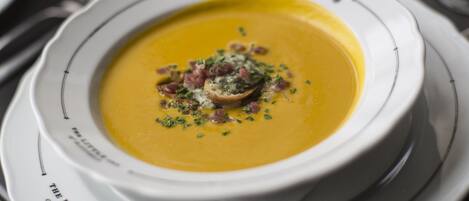 A bowl of soup with garnishes on a plate.