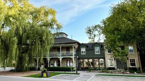 A historic building with a porch and multiple windows, surrounded by trees. - The Little Inn of Bayfield (Bluewater)