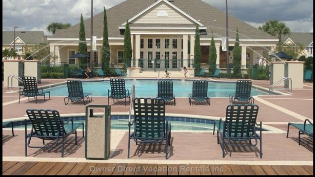 A pool area with multiple lounge chairs and a building in the background. - Villas at Seven Dwarf by FunQuest (Kissimmee)