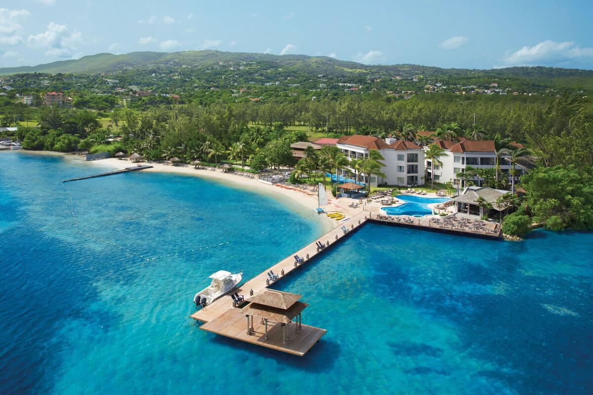 Ein Resort mit großem Schwimmbad, Strand und einer anlegenden Mole.