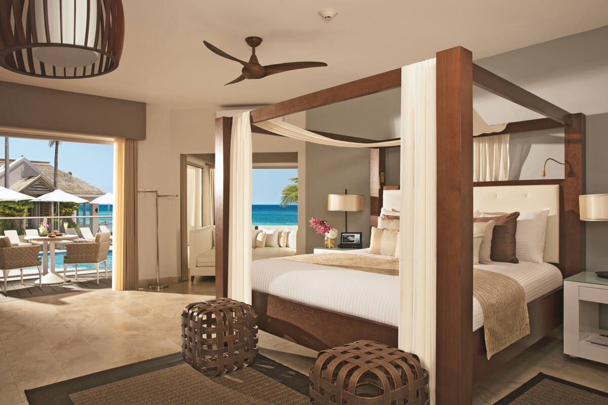 Ein geräumiges Schlafzimmer mit einem großen Bett, einem Deckenventilator und Blick aufs Meer.