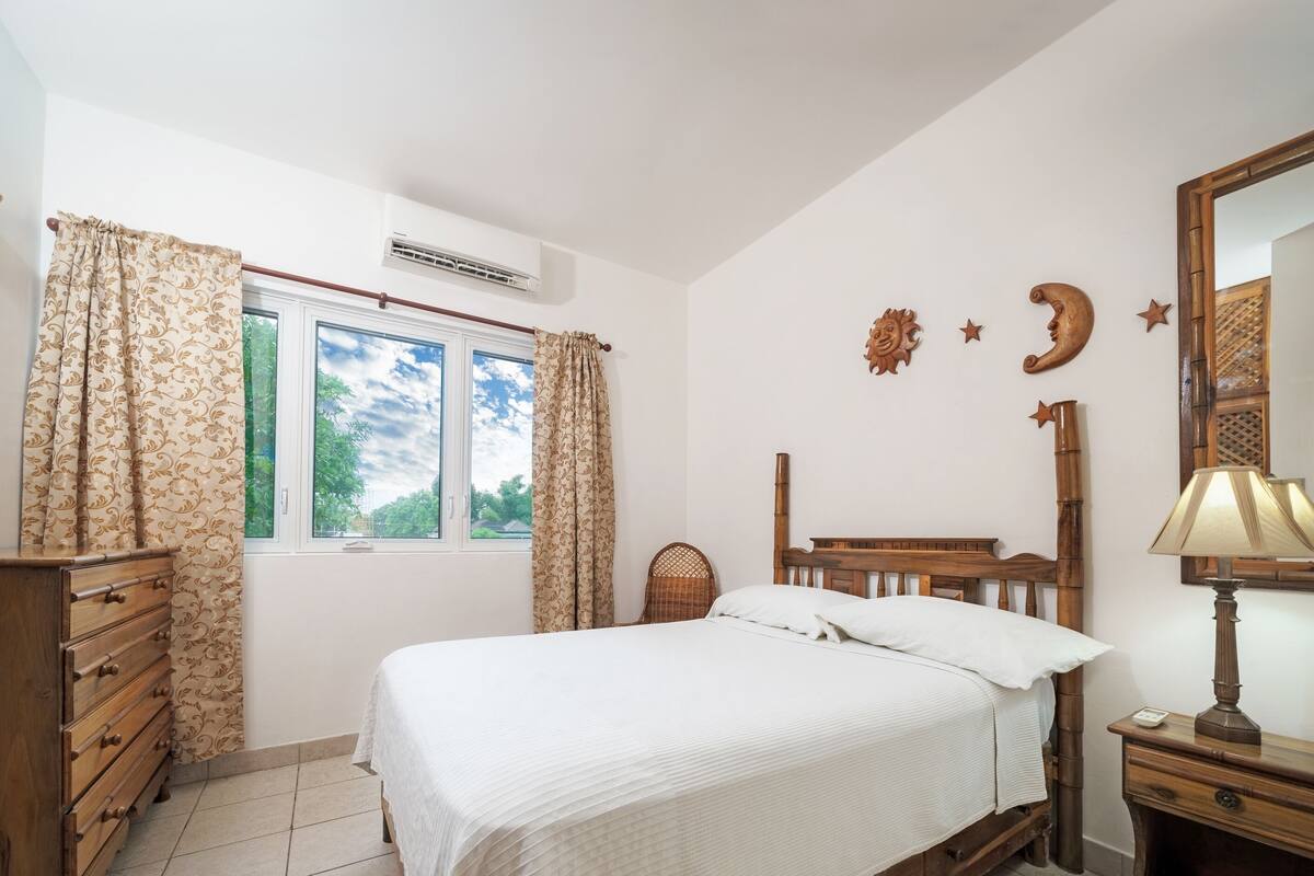 Un dormitorio con cama, cómoda de madera y mesita de noche con lámpara.