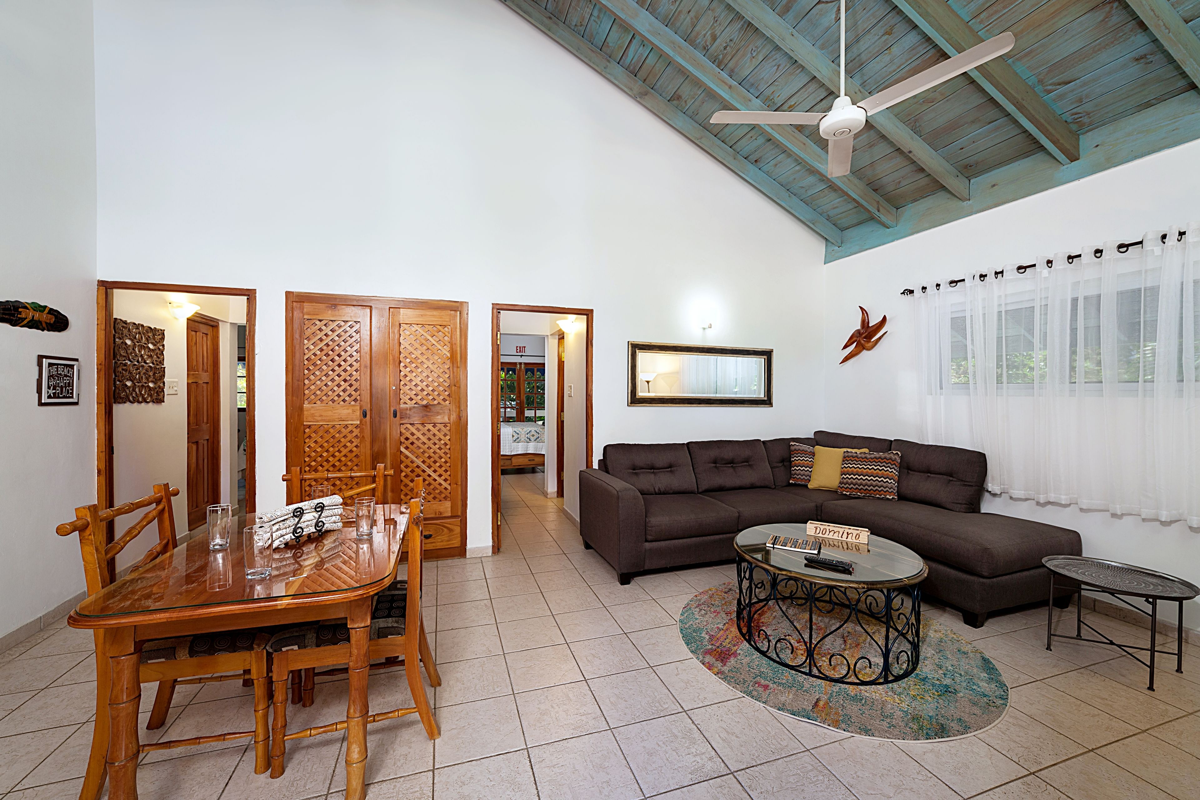 A living room with a wooden dining table, a brown sofa, and a ceiling fan.