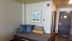 A bedroom with a bed, pillows, a framed picture, a door, and a light switch. - Holiday Inn Jonesboro by IHG (Jonesboro)