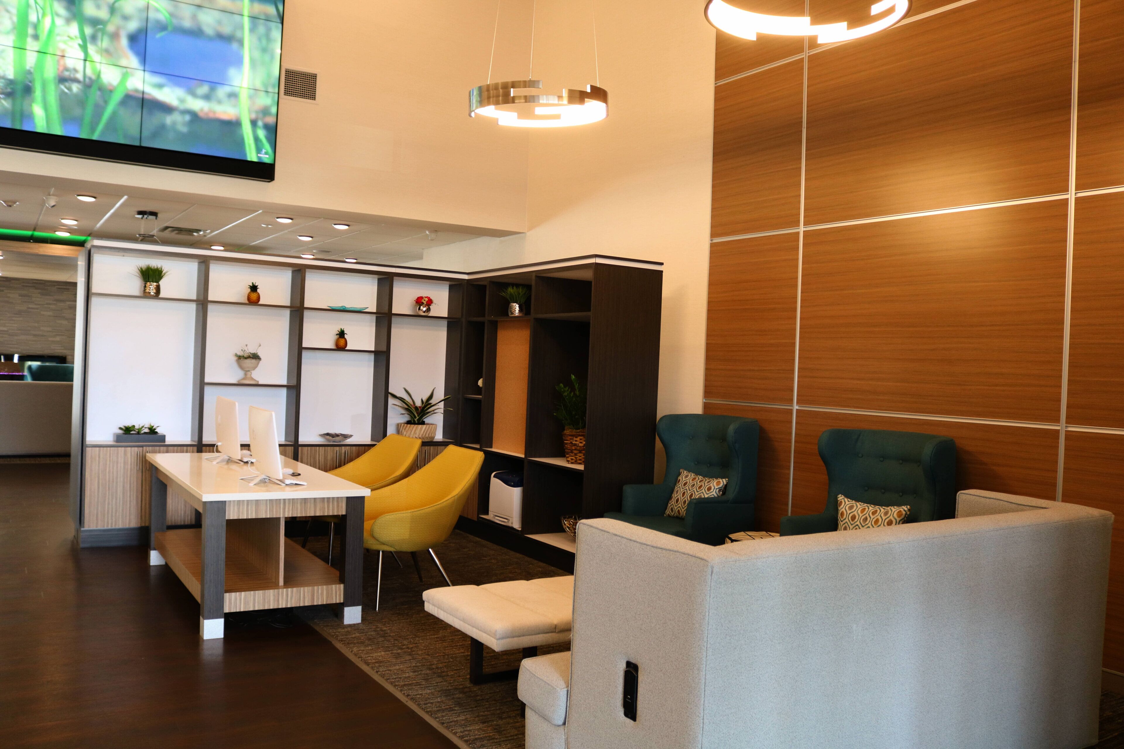 A modern lounge area with a flat-screen TV, seating, and a wooden wall.