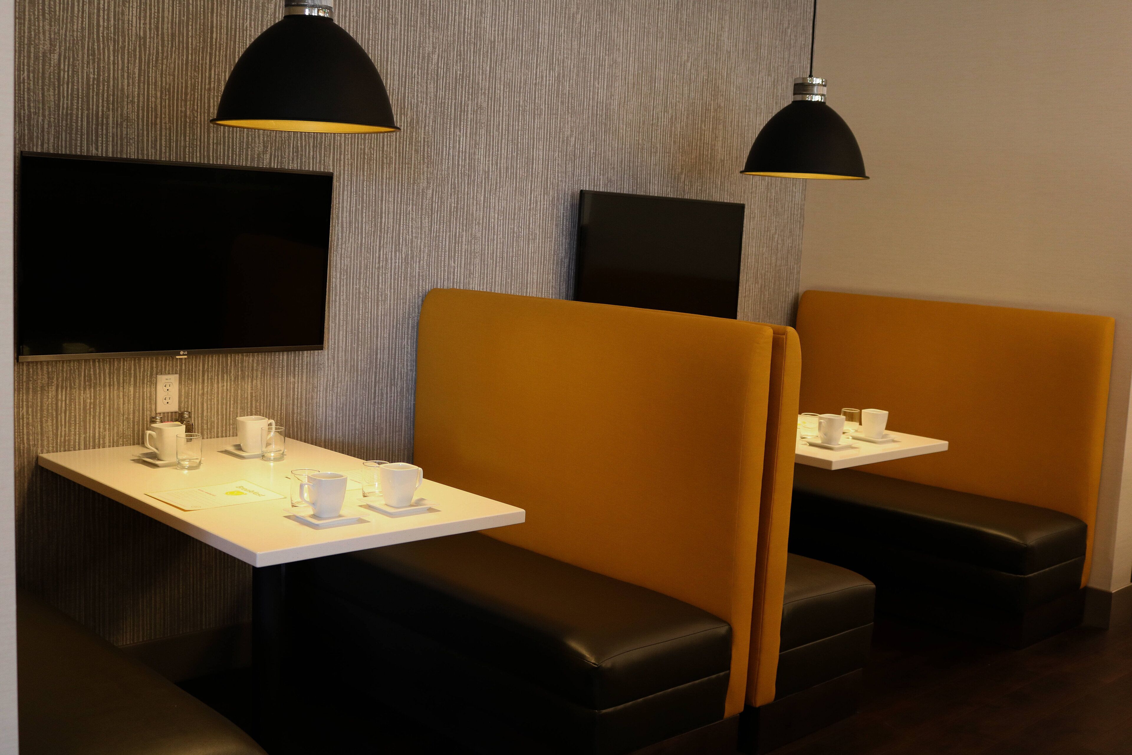 A modern restaurant interior with booths, tables, and pendant lighting.