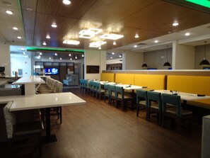 A restaurant interior with booths, tables, and a television screen.