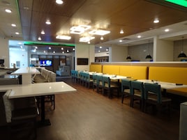 Un interior de restaurante con cabinas, mesas y una pantalla de televisión.