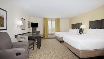 A hotel room with a desk, two beds, a chair, and a television.
