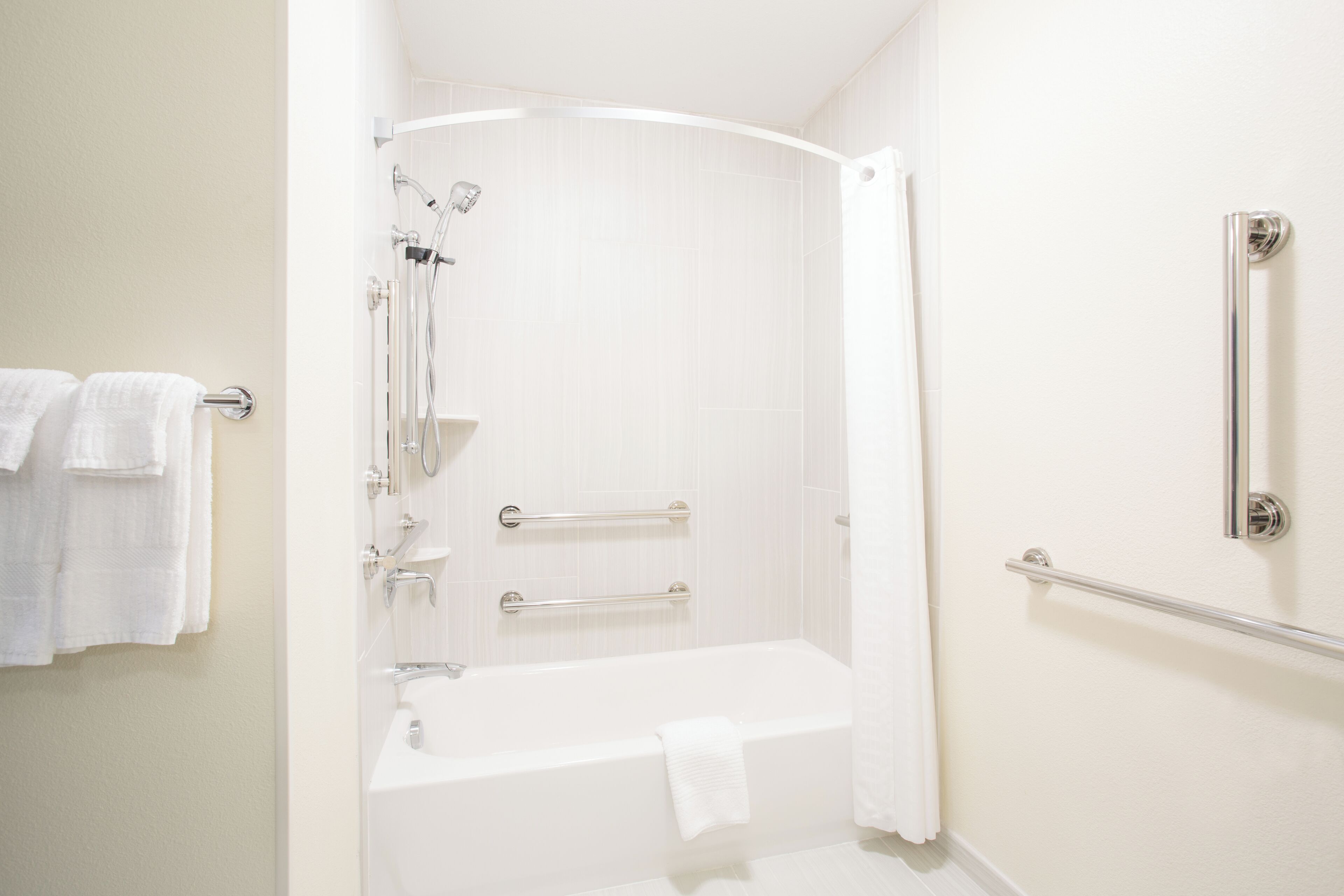 Une salle de bain moderne dotée d’une douche à l’italienne, d’une baignoire et d’une barre d’appui.