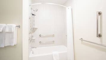 Une salle de bain moderne dotée d’une douche à l’italienne, d’une baignoire et d’une barre d’appui.