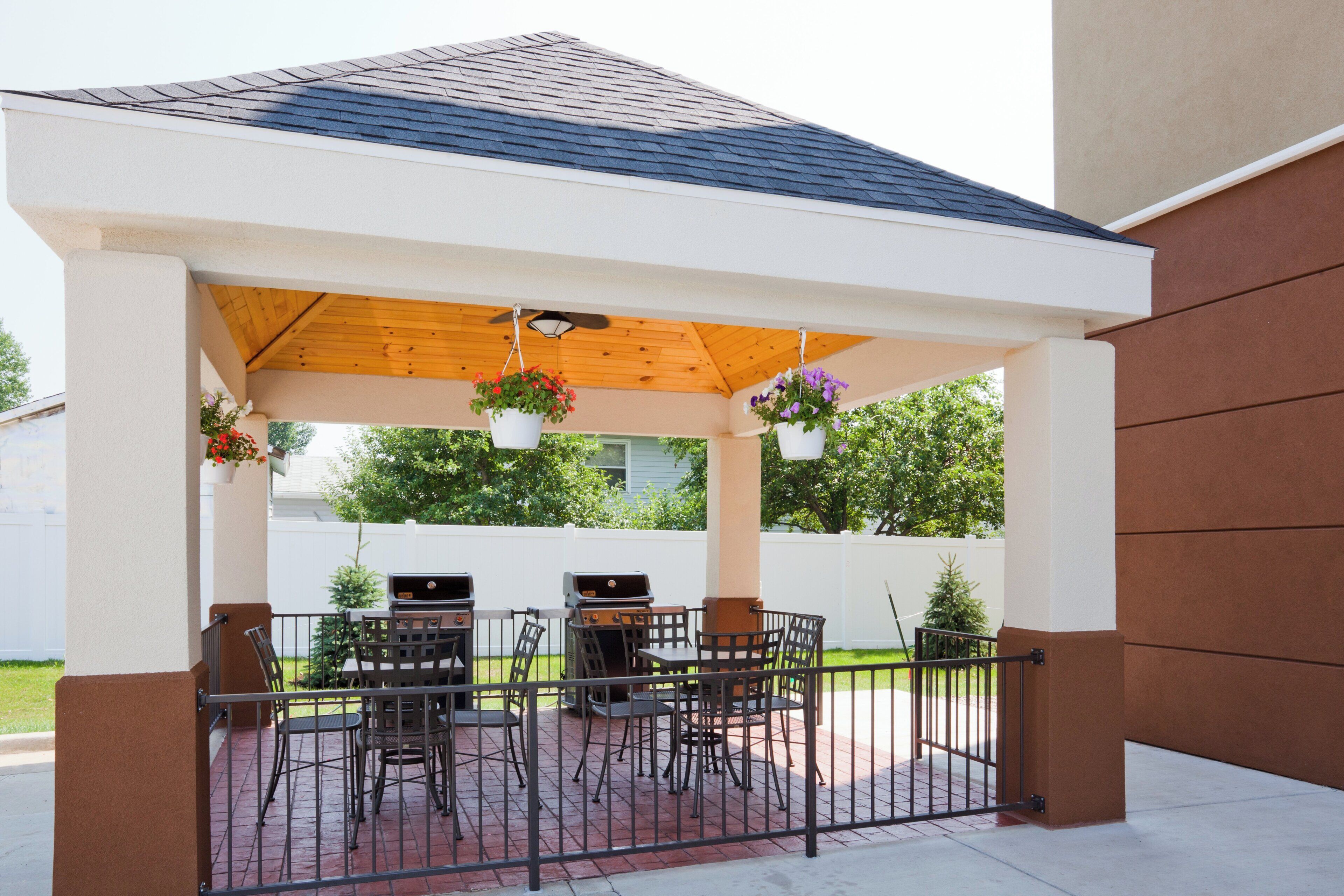 A covered patio with two barbecue grills, a table, and chairs.