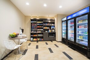 A self-service kiosk area with a microwave, seating, and beverage dispensers. - Candlewood Suites Longmont - Boulder Area by IHG (Longmont)