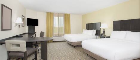 A hotel room with a desk, two beds, a TV, and a window with curtains.
