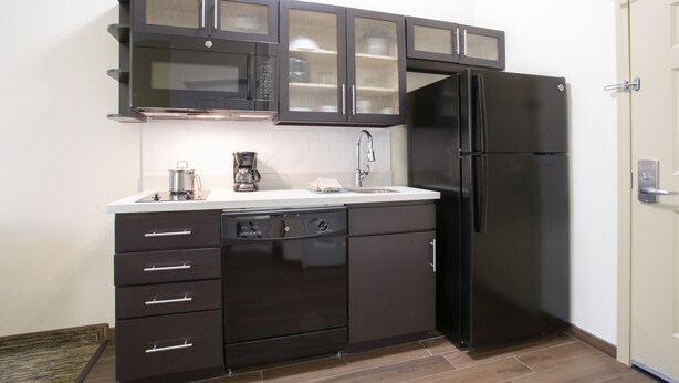 Una cocina compacta con armarios oscuros, un refrigerador negro y un lavavajillas.