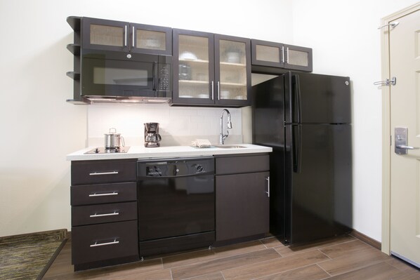 A compact kitchen with dark cabinetry, a black refrigerator, and a dishwasher. - Candlewood Suites Longmont - Boulder Area by IHG (Longmont)