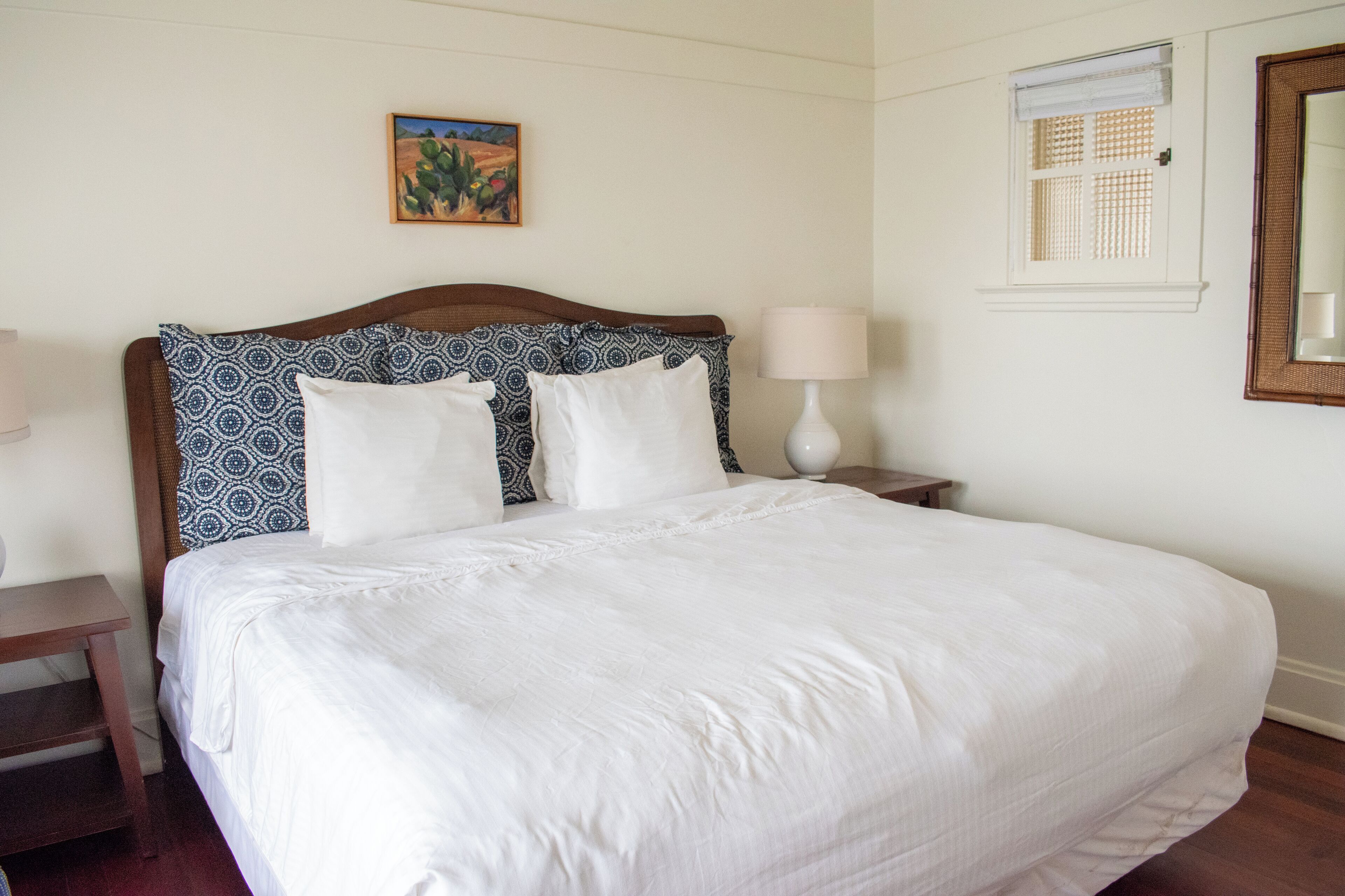 A neatly made bed with a patterned headboard, a bedside lamp, and a small table.