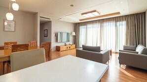 A modern hotel room with a dining area, a sofa set, and a flat-screen TV. - Elysian Gangchon Resort (Chuncheon)
