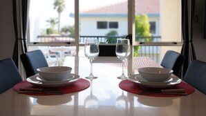 A dining table with two bowls, two wine glasses, and a red placemat. - Pacific Palms Resort (Tauranga)