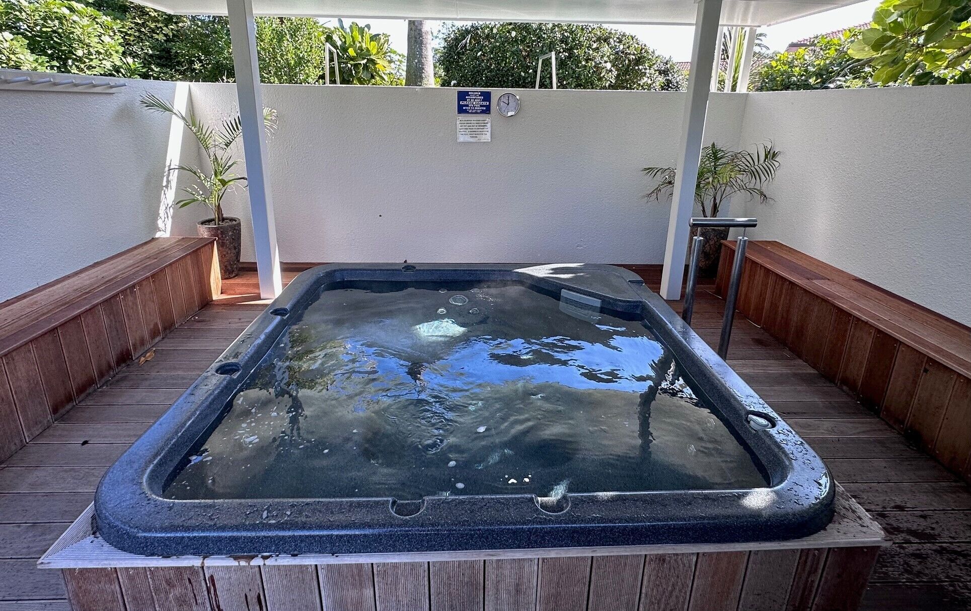 Ein Whirlpool mit Holzterrasse und einer weißen Wand im Hintergrund.