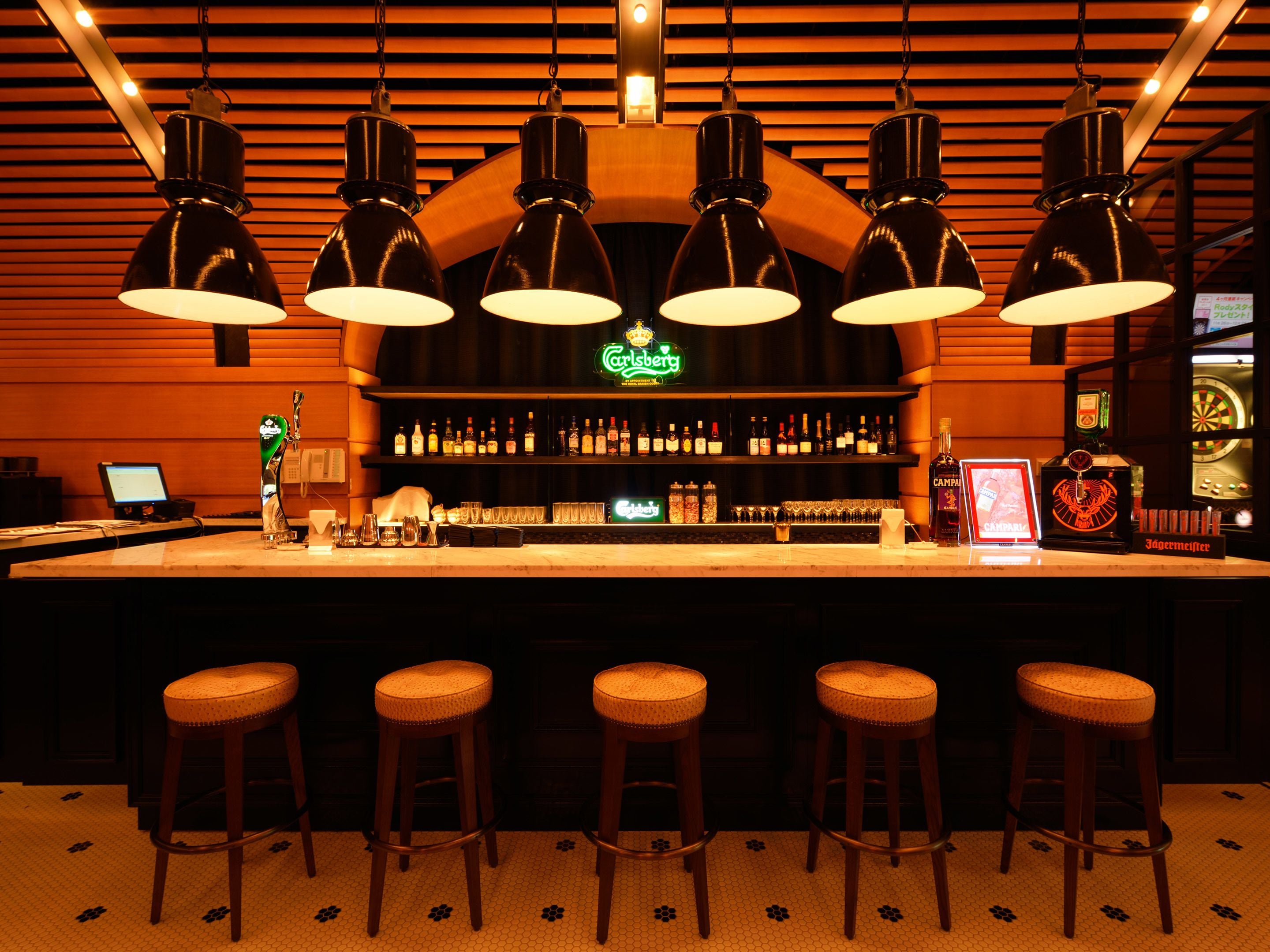 A bar area with multiple stools, a bar counter, and overhead lighting.