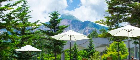 A patio with outdoor seating and umbrellas, overlooking a mountain range.