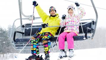 Two people on a ski lift, one in a yellow jacket and the other in a pink jacket.