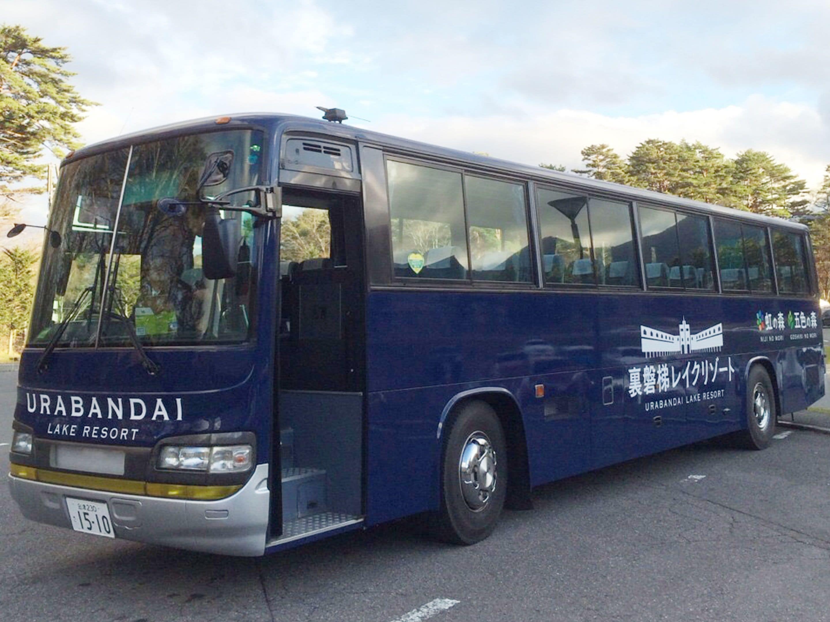 A blue bus with "URABANDAI LAKE RESORT" written on the side, parked on a road with trees in the background.
