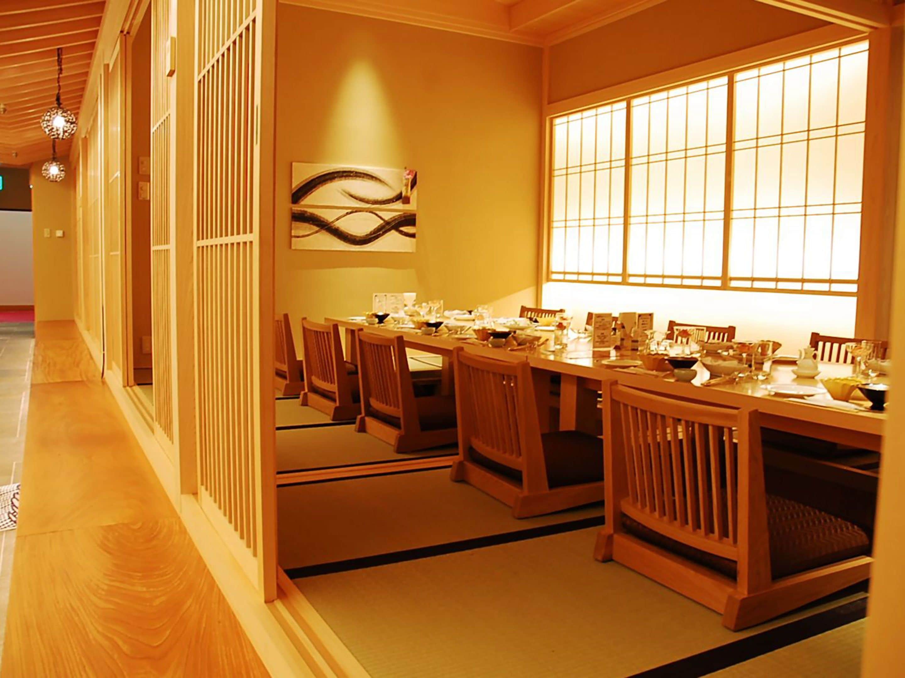 A traditional Japanese-style dining room with tatami mats, wooden furniture, and shoji screens.