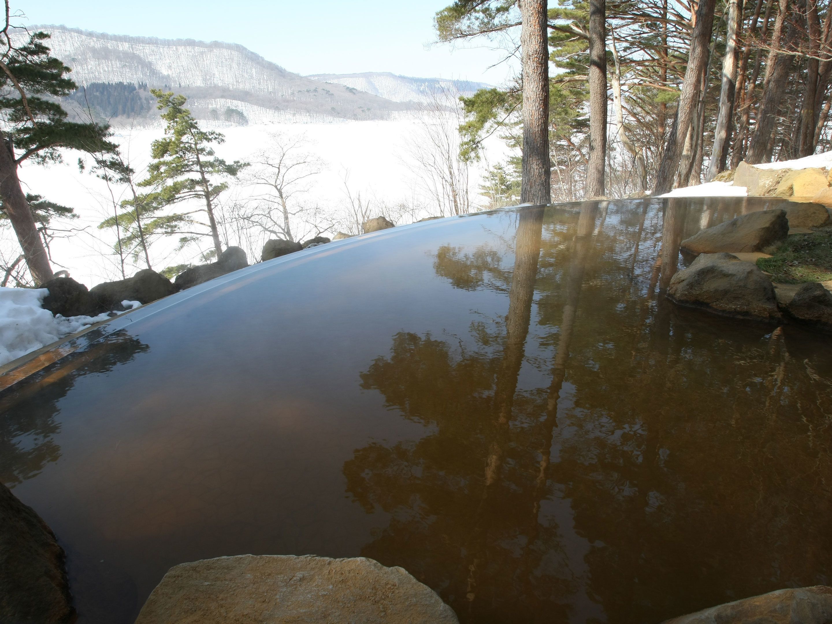 Un cadre extérieur paisible, avec une étendue d’eau calme entourée de rochers et d’arbres.