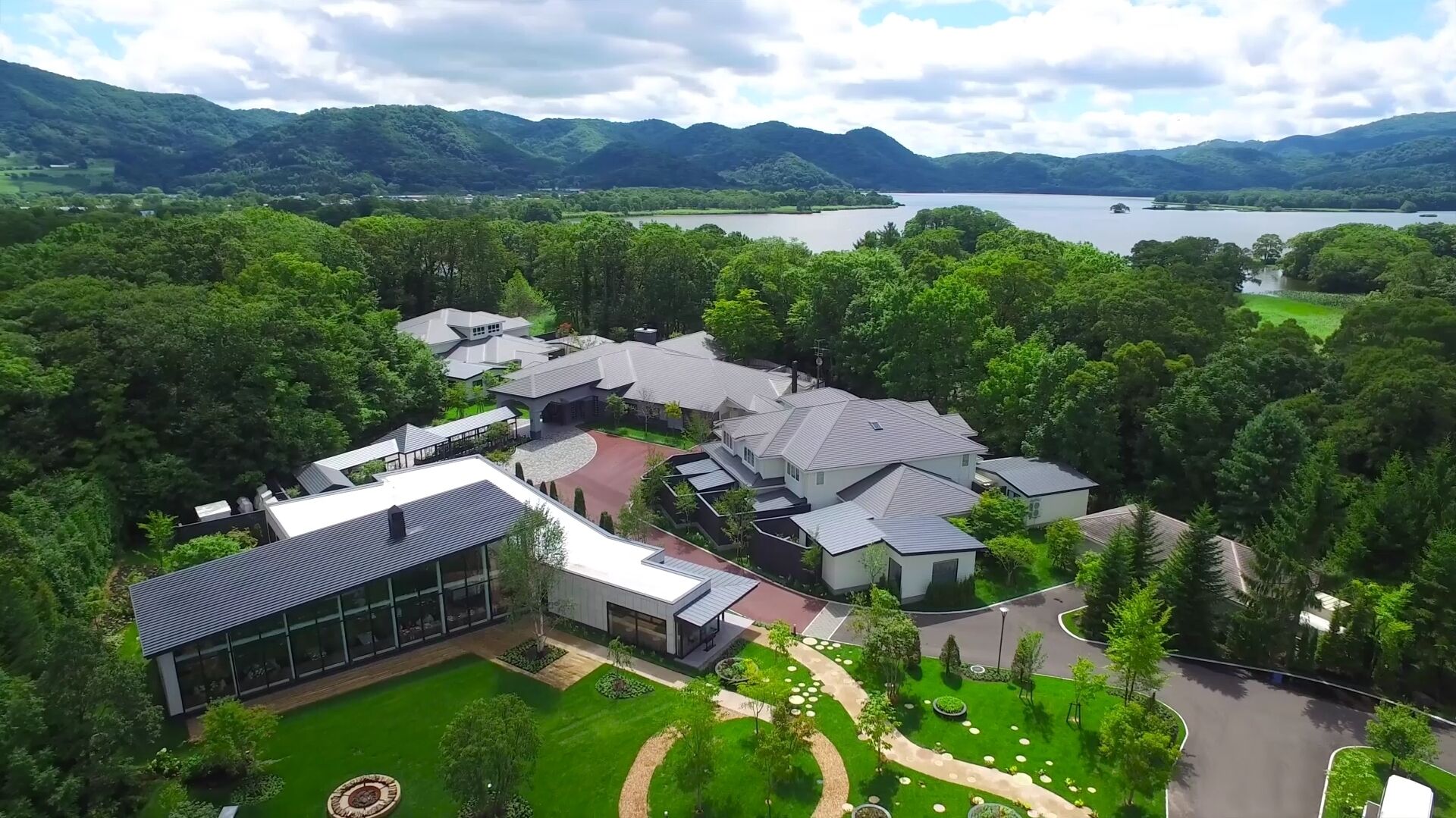 A residential area with modern houses, a large lake, and surrounding hills.