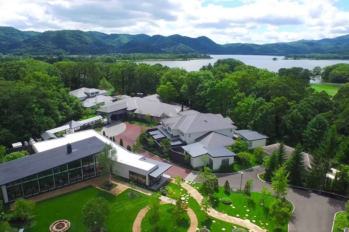 A residential area with modern houses, a large lake, and surrounding hills.