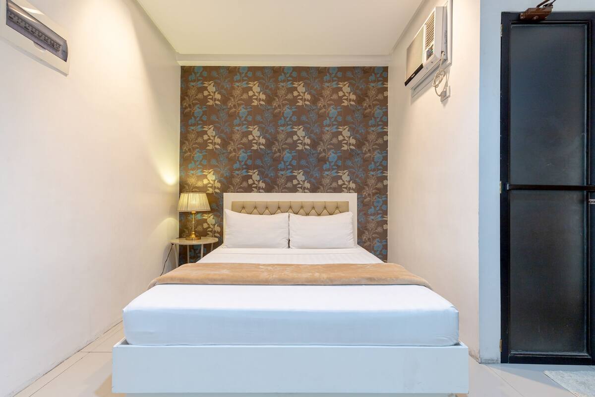 A neatly made bed with a white headboard and a beige throw blanket.
