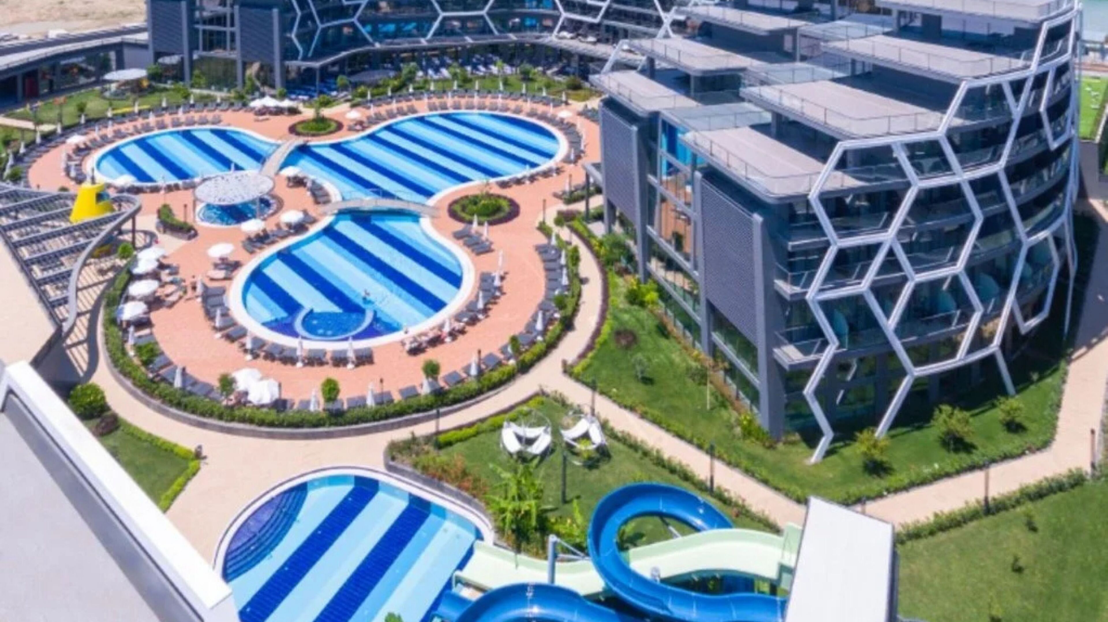 A modern hotel with multiple swimming pools, a central courtyard, and contemporary architecture.