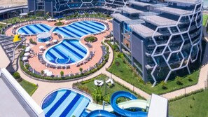 A modern hotel with multiple swimming pools, a central courtyard, and contemporary architecture.
